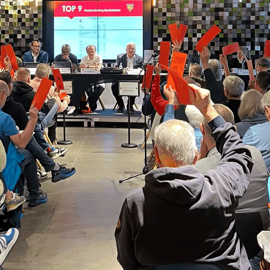 Bei der Tagung eines Basketballvereins wird mit roten Zetteln in der Hand abgestimmt.