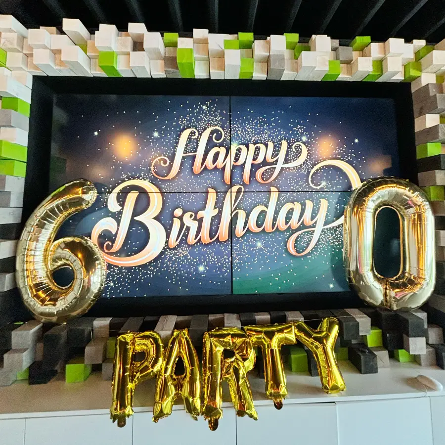 Ein großes Display mit einem Geburtstagsgruß und goldenen Luftballons als Dekoration drumherum.