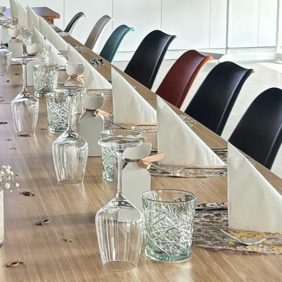 Ein langer Holztisch mit Stühlen, einer reduzierten, aber eleganten Tischdekoration und Gedecken.