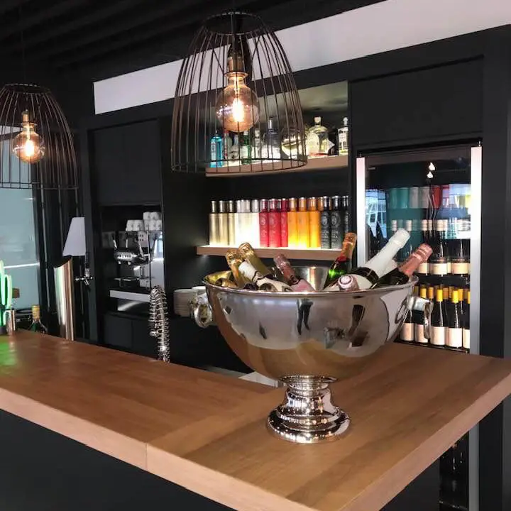 Ein Sektkübel steht an einer kleinen Bar, die im Hintergrund dekorativ beleuchtet ist.